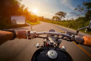 Driver riding motorcycle on the empty asphalt road