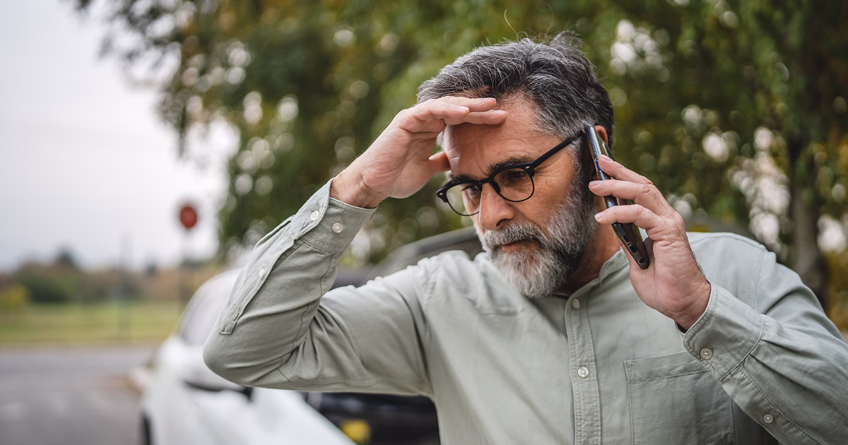 Worried man on the phone near a car on the roadside.