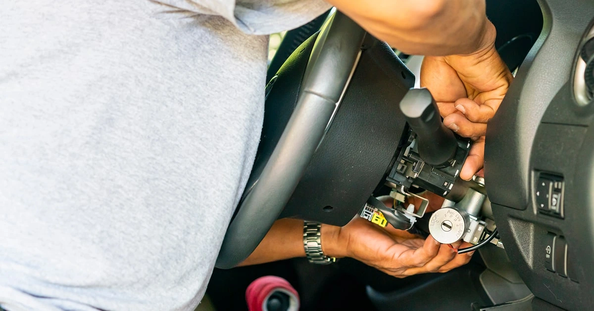 Mechanic repairing car ignition switch inside steering column