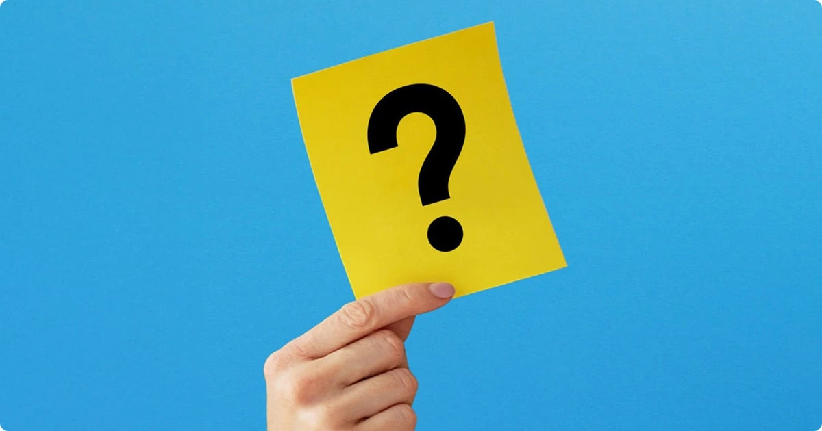 Hand holding yellow card with question mark symbol