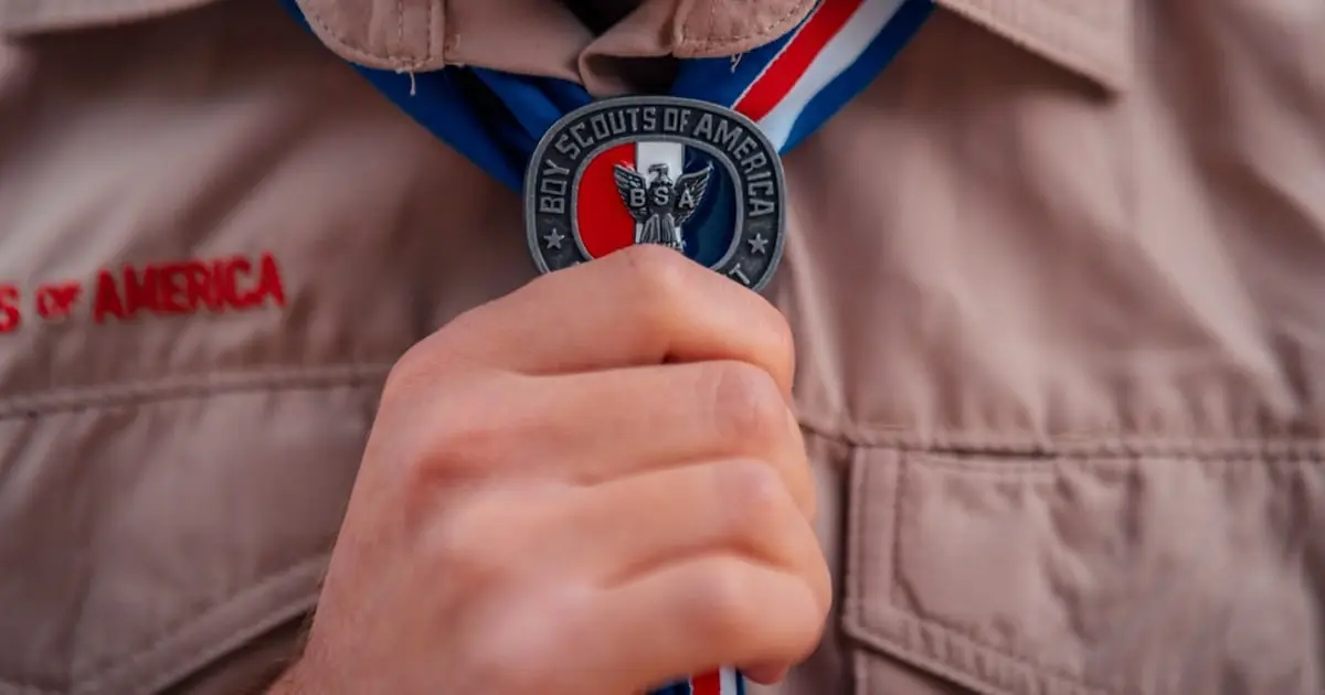 Boy Scouts of America scout uniform with hand holding medal