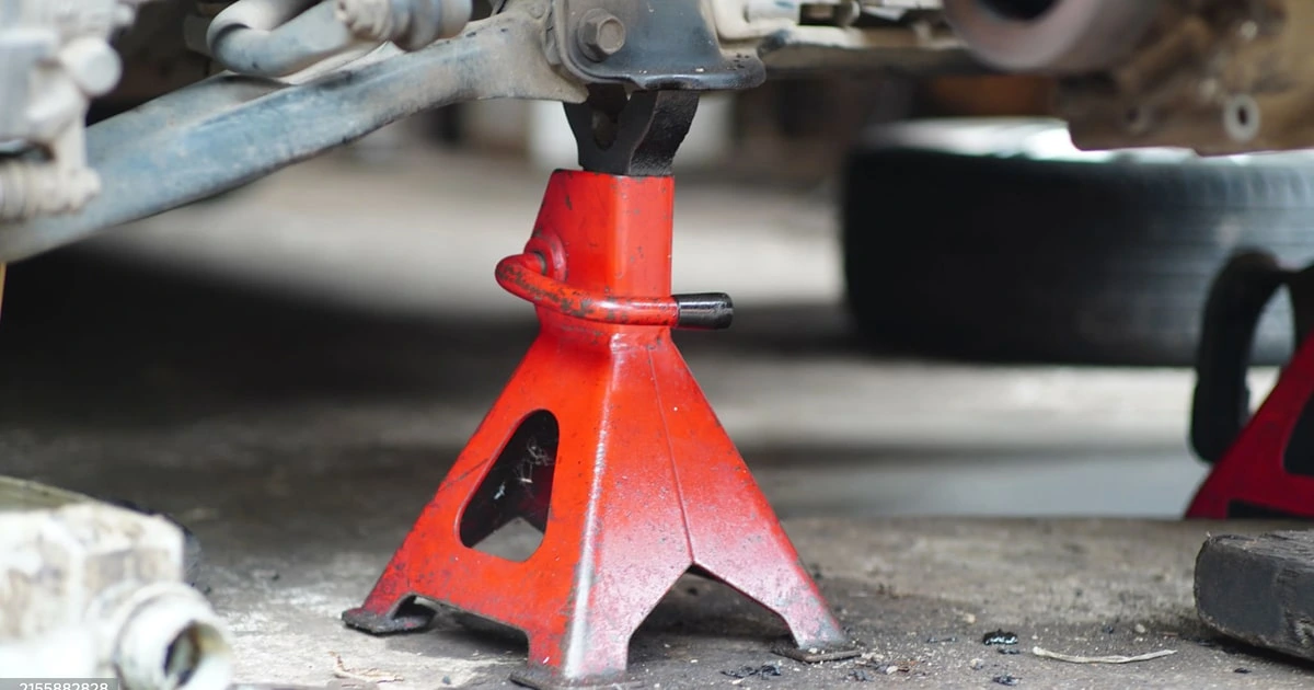 Red jack stand supporting vehicle during car repair