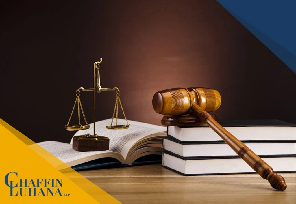 Judge’s gavel resting on stacked law books beside golden scales of justice on a wooden desk.