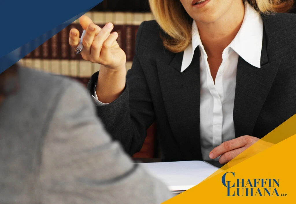 Female attorney in a business suit consulting with a client across a desk in a law office.