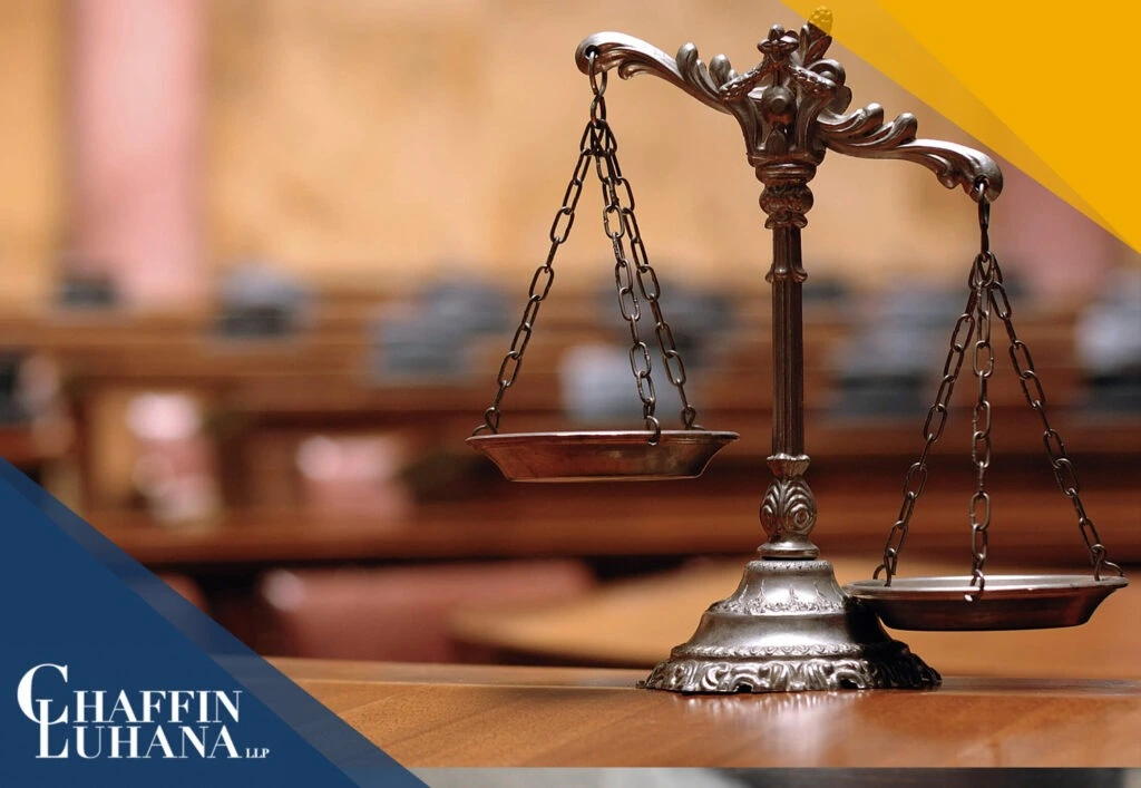 Bronze scales of justice displayed on a courtroom desk with blurred benches in the background.