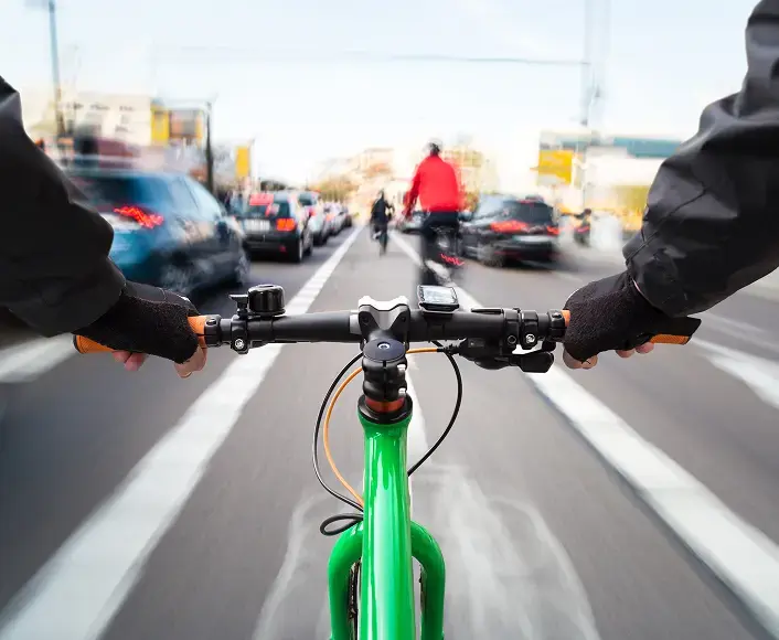 Cyclist riding through city traffic on a green bike, representing bicycle accidents and legal advocacy for injured riders.