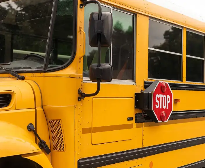 Close-up of a yellow school bus with a visible stop sign arm extended, representing school transportation safety and accident awareness.